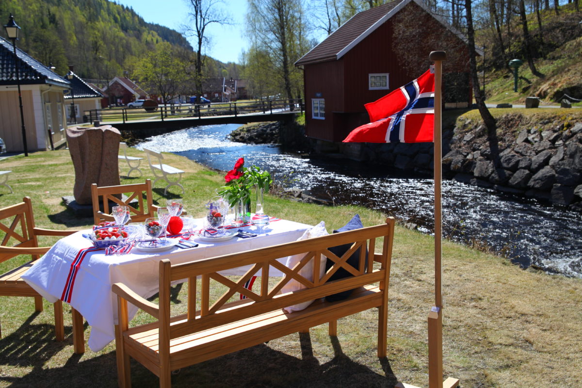 Dekket 17.mai bord med norsk flagg på gresset utenfor Verket Interiør på Bærums Verk i strålende sol.