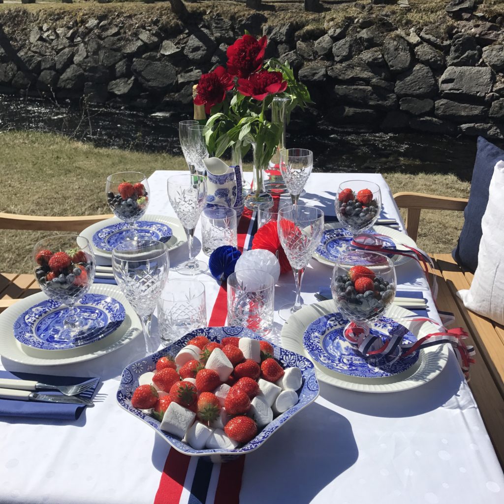 Dekket 17.mai bord med norsk flagg på gresset utenfor Verket Interiør på Bærums Verk i strålende sol. Møbler i teak fra Skagerak Denmark.